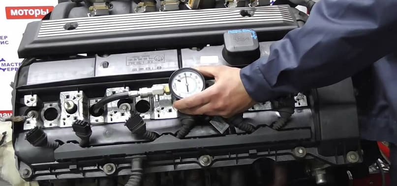 механик замеряет компрессию мотора