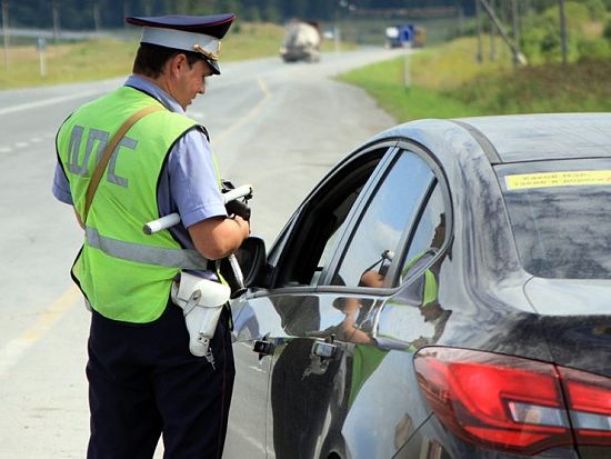 сотрудник ГИБДД проверяет автомобиль